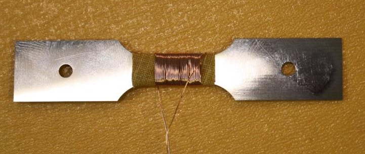 Eprouvette « habillée » d’une bobine de fil de cuivre pour mesure de propriétés magnétiques après fatigue. Collaboration avec Dr. Abdelkader BENABOU L2EP, Université de Lille